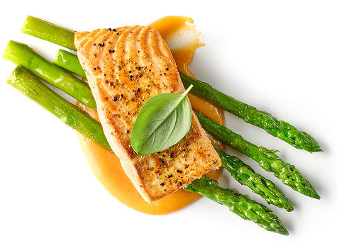 Baked Atlantic salmon with steamed asparagus and golden sauce garnish.