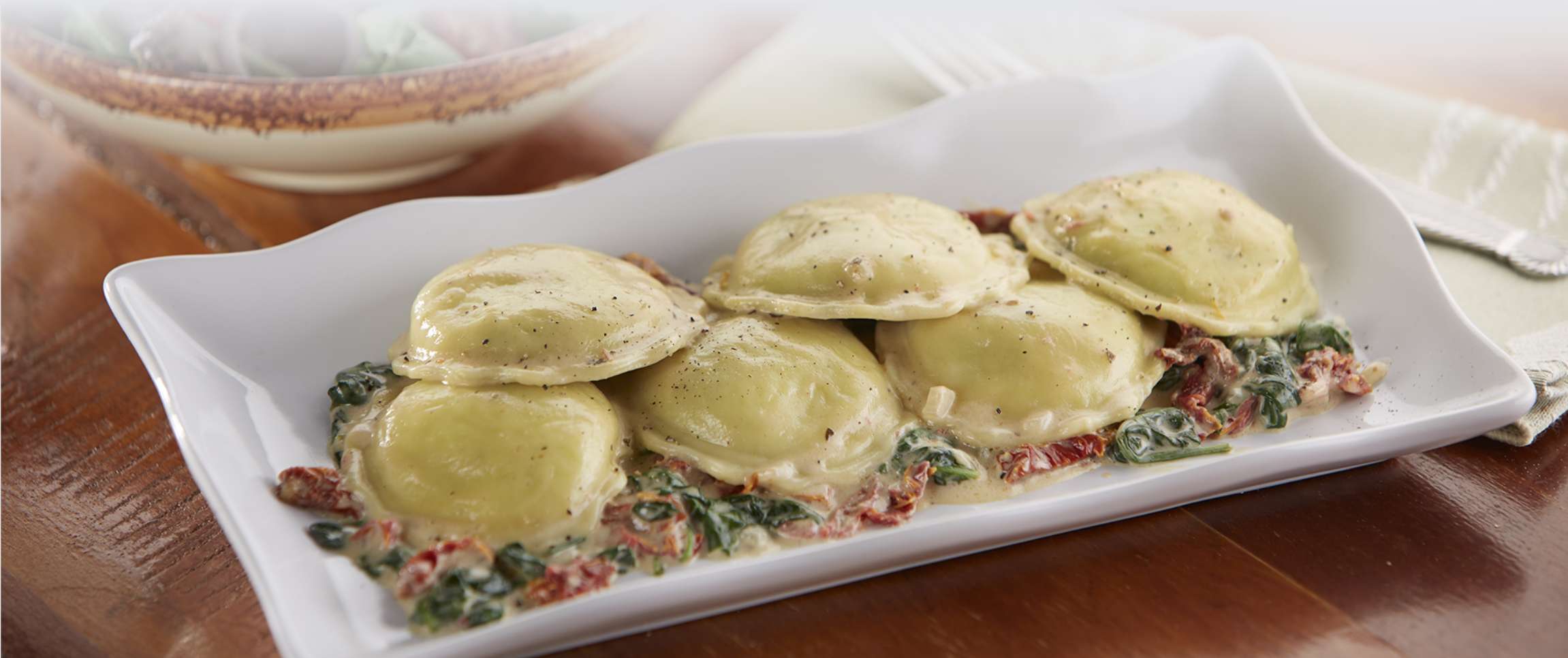 Cheese Ravioli and Pesto Cream Sauce with Sun-dried Tomatoes and Baby Spinach