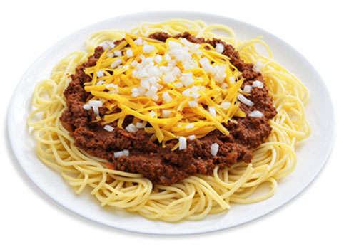 Cincinnati chili with beef chili on a pile of spaghetti, topped with cheese and onion dices.